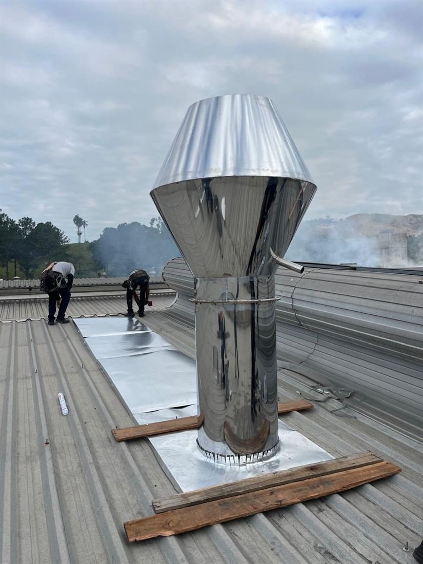 Equipe da WL trabalhando sobre telhado industrial ao lado de chaminé em aço inox recém instalada em Brusque, SC